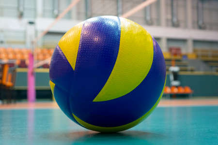 Yellow-blue volleyball on the floor in the gym, team of athletes playing volleyballの写真素材
