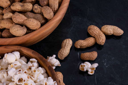 Peanuts with Popcorn in golden wood bowl on black marble table