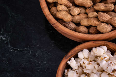 Peanuts with Popcorn in golden wood bowl on black marble table
