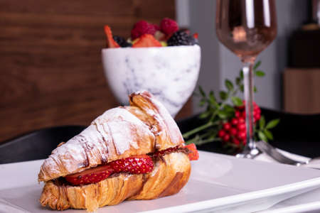 French style romantic summer picnic setting. Flat-lay of glasses of rose wine, fresh strawberries, croissants, brie cheese, hat, sunglasses, peony flowers, square crop. Outdoor gathering conceptの写真素材
