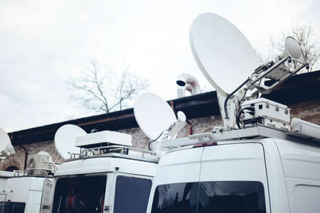 TV Media Television Trucks with multiple Satellite parabolic antennas and fiber optic cables preparing to report live a political sport or other news eventの写真素材