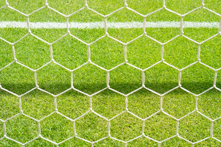 Close up detail of a soccer net against green grass