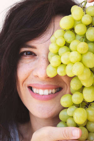 portrait of attractive caucasian smiling blur woman isolated on white studio shot with green grapes