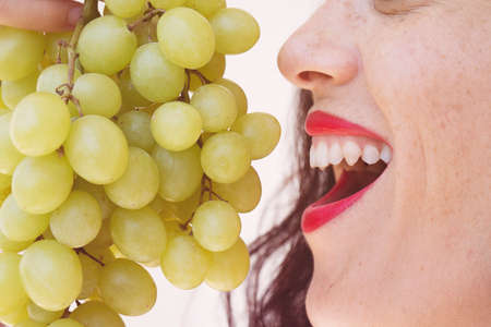 sexy woman eating green grapes, sensual red lips.の写真素材