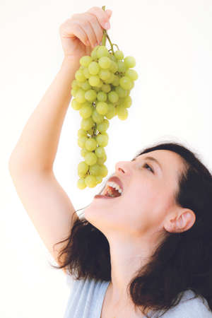 Close up shot of beautiful young woman eating grapes, isolated on white. Vertical imageの写真素材