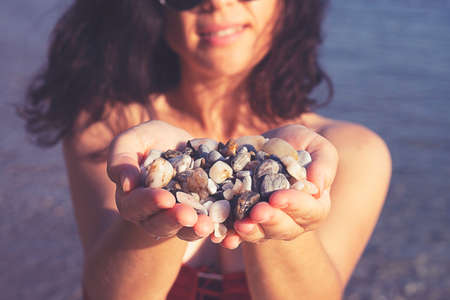 Young woman holding on her hand the beautiful colorful pebbles of Greek beaches.の写真素材