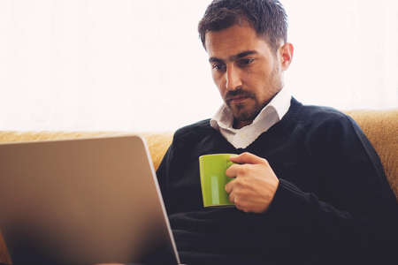Young man working at home and drinking a cup of coffee