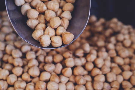 spoon with roasted hazelnuts on hazelnut background. Prepared with the harvest of hazelnuts. Flat...