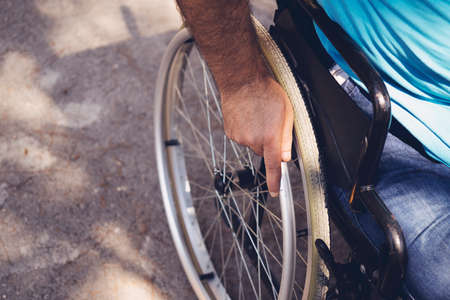 Close up photo of Young disabled man holding wheelchair outside in parkの写真素材