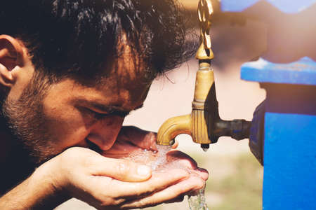 Caucasian young man preparing to drinking water from the retro fountain.の写真素材