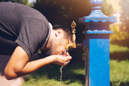 Caucasian young man preparing to drinking water from the retro fountain.の写真素材