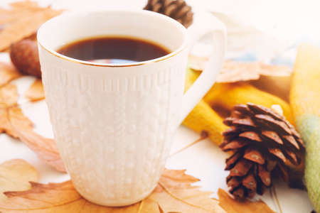 Autumn composition concept background. Dark coffee cup, with autumn bright leaves, pine cones on...