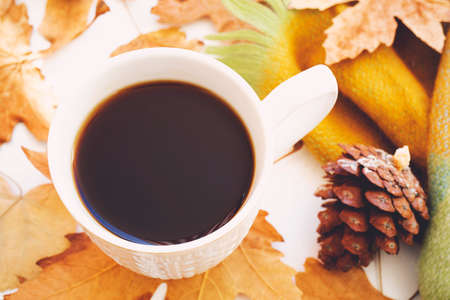 Autumn composition concept background. Dark coffee cup, with autumn bright leaves, pine cones on...