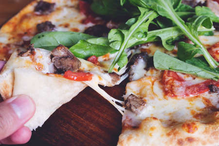 meal time at pizzeria, man taking a slice of the pizza shot with very thin depth of field
