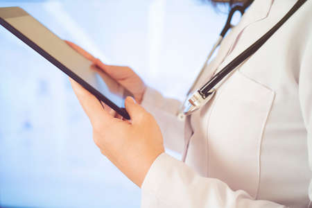 Woman doctor using tablet computer while standing straight in hospital