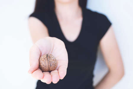 Detail of young womanâs hand, holding a handful of organic walnut. Selective focusの写真素材