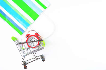 Red clock, shopping cart and paper bag on isolated white backgroun. Lack of time, waste of time, purchasing time, Shopping concept, Business concept.の写真素材