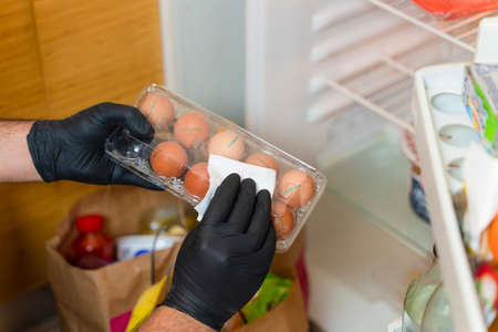 COVID-19: Is it necessary to clean your groceries delivered at home? Man in quarantine wiping...