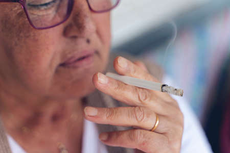 closeup of older woman holding a cigarette in her handsの写真素材