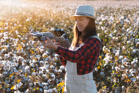 The female drone pilot walks into the field and inspects before the flight. Drone in woman hands. Farmer Woman checking agricultural productivity using drone technology.の写真素材