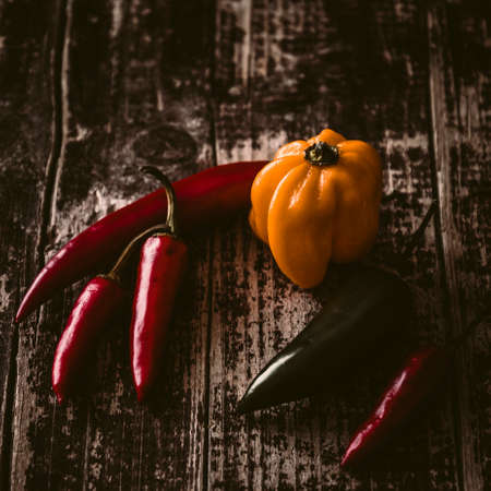 Variation of colored chilies lying on a wooden tableの写真素材