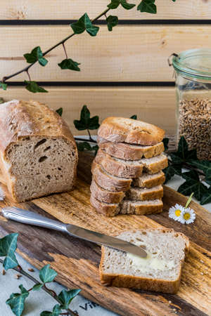 Homemade bread on a wooden board, decorated with ivy tendrils. Vertical.の写真素材