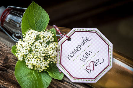 Glass bottle with homemade elderflower syrup lying on an old wood truss. Closeup.の写真素材