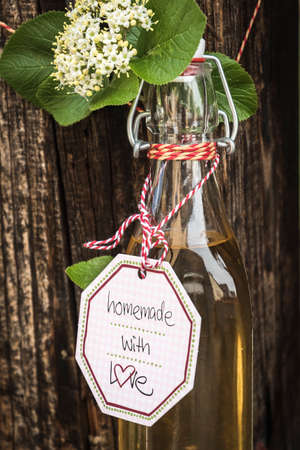 Glass bottle with homemade elderflower syrup bound on a wood truss.の写真素材