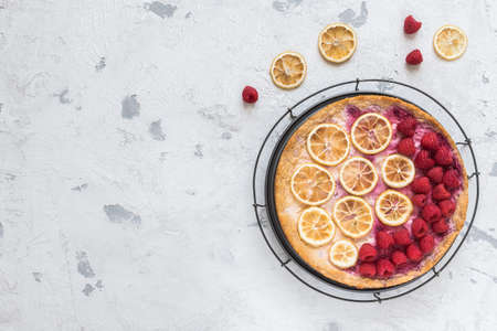 Cheese cake with raspberries and dried lemon slices on white background, top view with copy spaceの写真素材