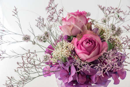 Closeup of bouquet of two pink roses and different purple and white flowers on white backgroundの写真素材