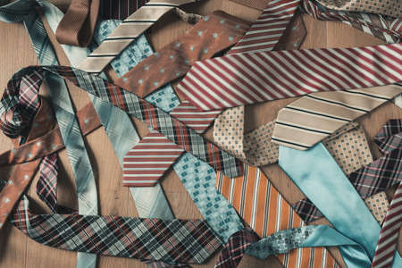 Messy pile of colored and patterned ties on wooden background from top viewの写真素材