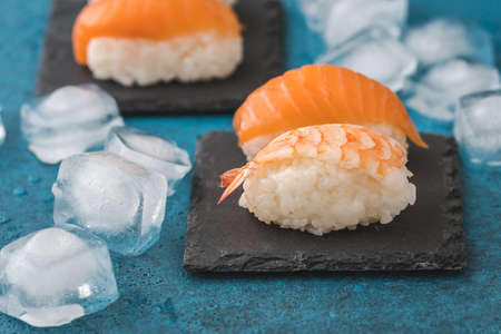 Closeup of nigiri sushi on slate with ice cubes on blue backgroundの写真素材