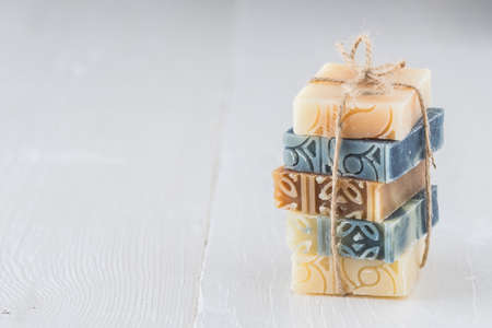 Stack of assorted natural soap bars on white wood. Stock photo with copy space.の写真素材