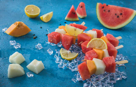 Melon skewers on ice on blue backgroundの写真素材