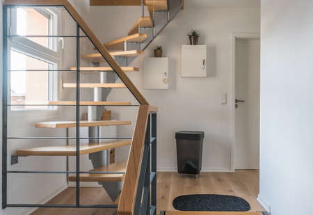 Staircase of a private house with modern stairs. Steel frame with wooden steps, white and gray walls, harmonious color concept.の写真素材