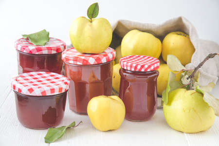Glasses with homemade quinces jelly and ripe quinces on white wooden backgroundの写真素材