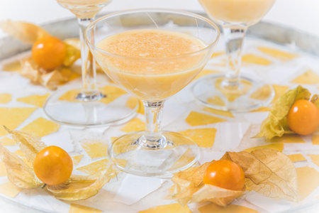 Glass with eggnog and physalis fruits on a round trayの写真素材