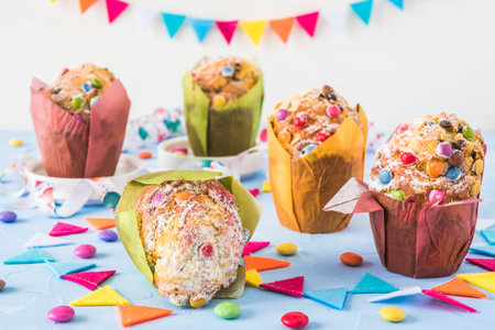 Colorful muffins on blue, decorated with a party garland and chocolate beans for a party, birthday, carnival, new yearの写真素材