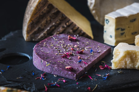 Variation of different cheeses on a slate, focus on purple lavender cheese with flowers and herbs