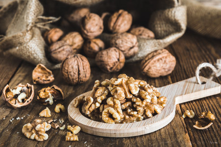 Whole and peeled walnuts on a rustic wooden table, focus on the walnut kernelsの写真素材
