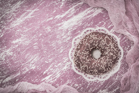 Pink glazed donut on a pink and white painted background, color desaturated for monochrome vintage look, top view with copy spaceの写真素材