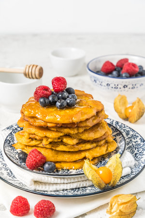 Pile of vegan pancakes with berries and syrup on white background, vertical with copy spaceの写真素材