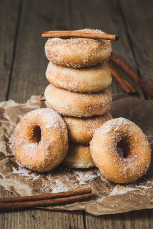 Sugared stacked mini donuts with cinnamon on a wooden table, verticalの写真素材