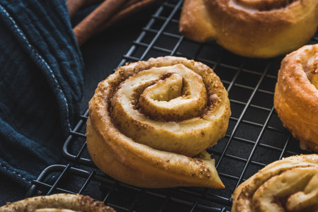 Closeup of a homemade cinnamon roll on a cooling rack on dark blue background.の写真素材