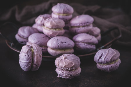 Homemade purple cookies with white chocolate cream filling in macarons style on brown background, focus in frontの写真素材