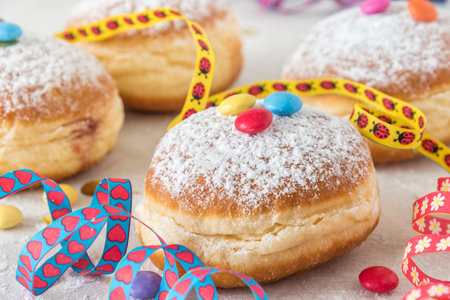 Krapfen, Berliner or donut with streamers, confetti and chocolate beans on white background. Colorful carnival or birthday image.の写真素材