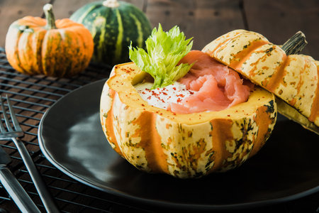 Stuffed oven pumpkin with sour cream and salmon on black plateの写真素材
