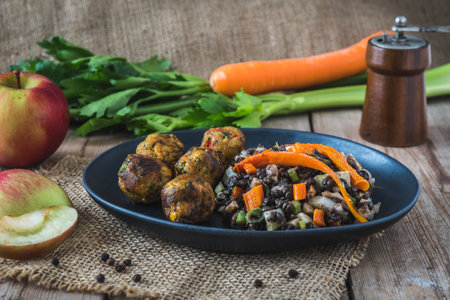 Grilled vegetable balls with lentil salad, celery, carrot and apple on a wooden table, vegan food conceptの写真素材