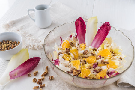 Chicory salad with orange and walnuts on white backgroundの写真素材