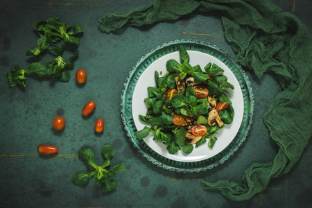 Fresh corn salad with mushrooms and roasted seeds on a white plate on green background, top viewの写真素材